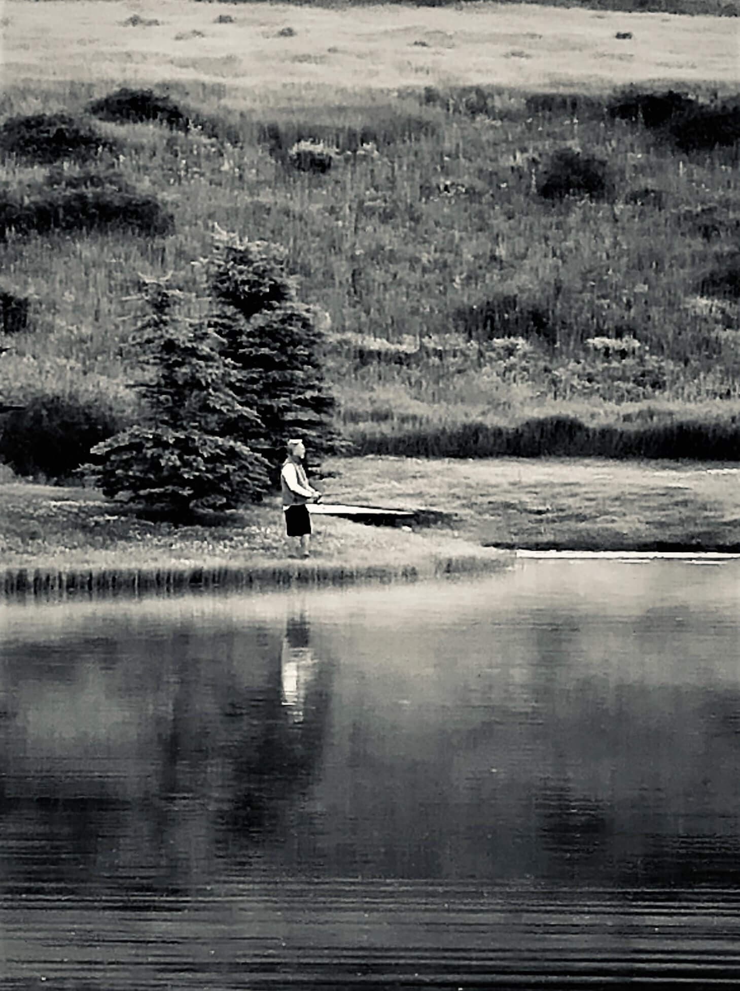 Person fishing by a serene lake